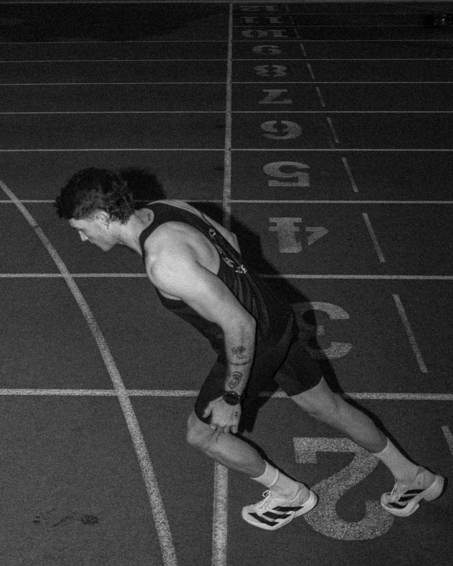 Overhead frame of a runner stretching across track lane numbers