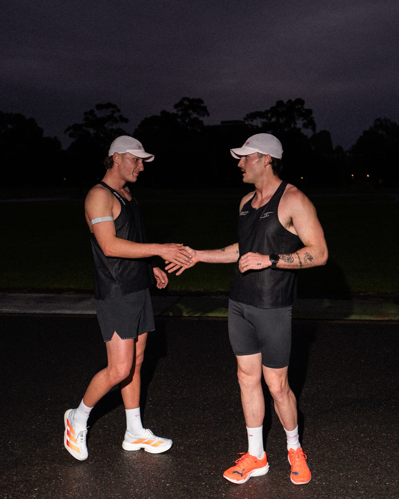 Two runners shaking hands after a night session