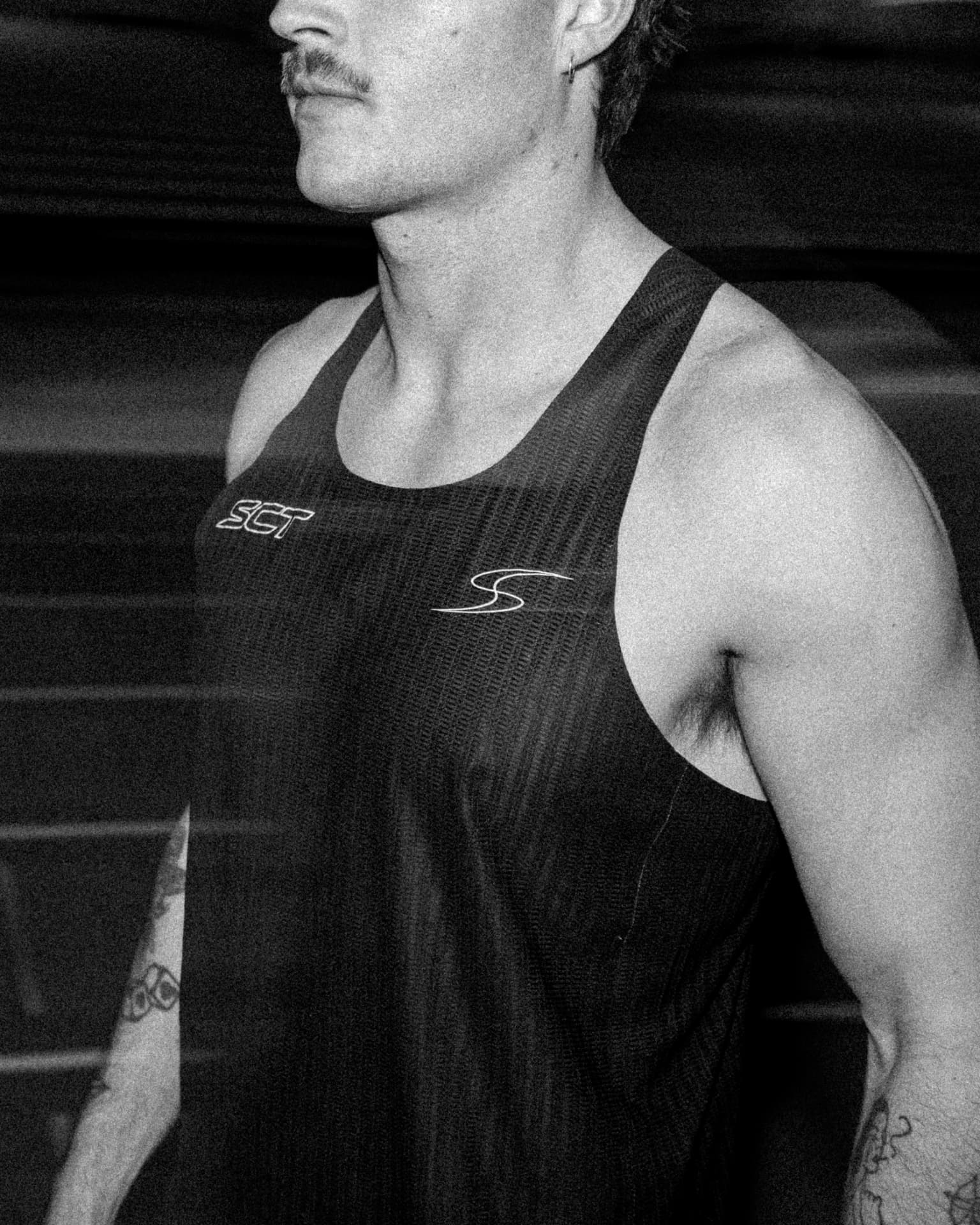 Detail of a black SCT singlet on an athlete at the track