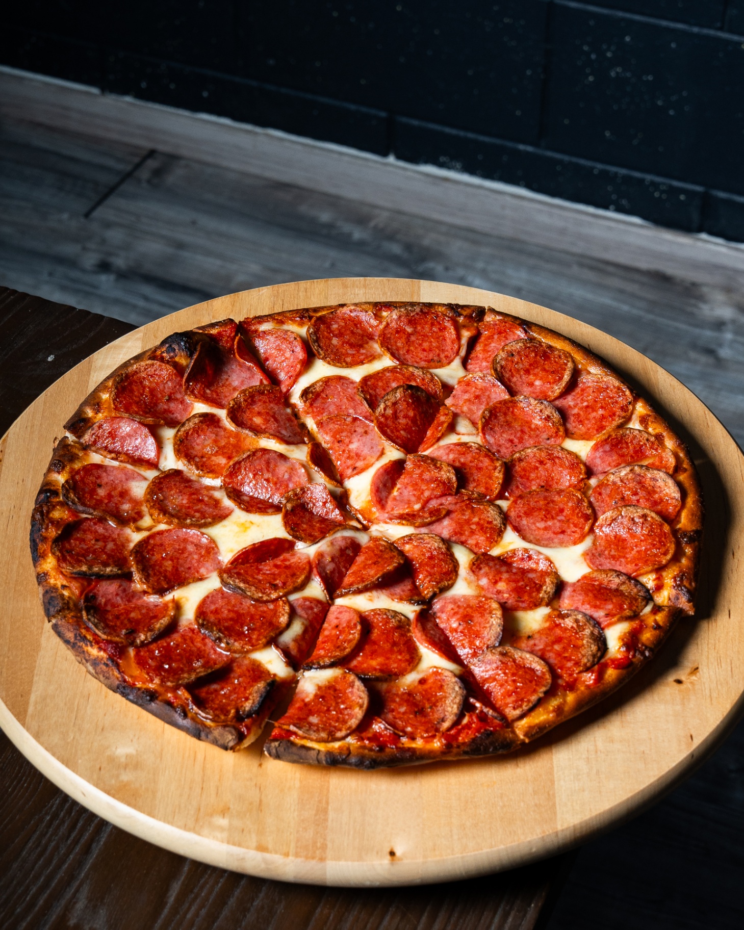 Whole pepperoni pizza on a wooden board at Pizzario