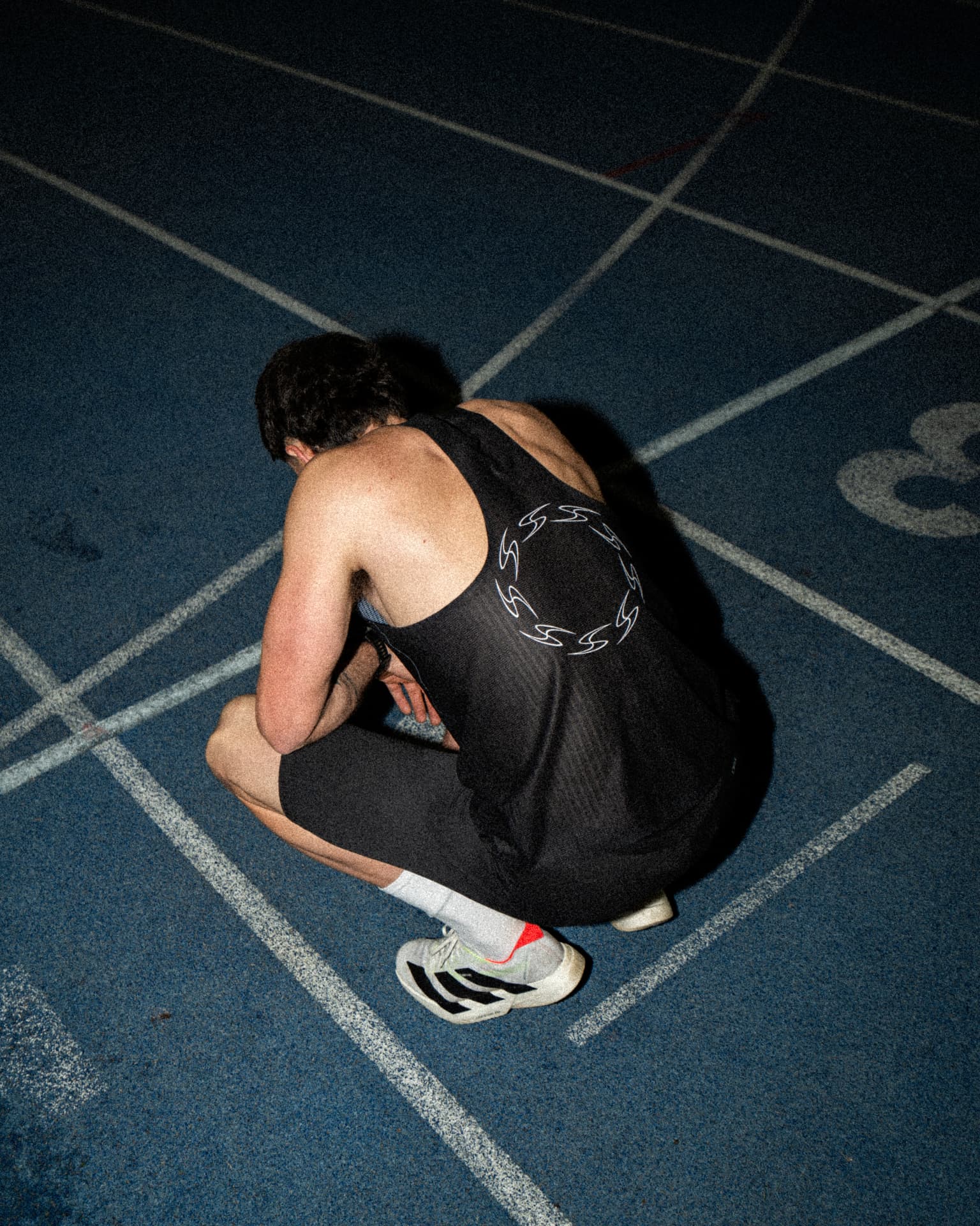 Athlete crouched on a blue track after a session