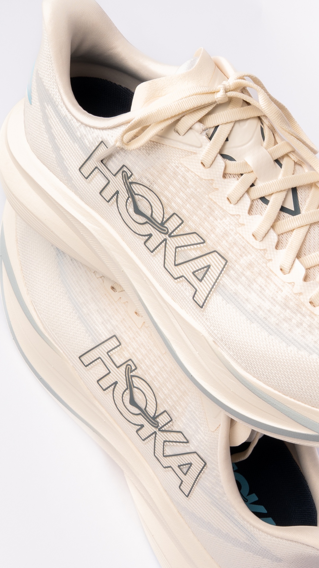 Two HOKA shoes showing the outline logo on cream mesh uppers